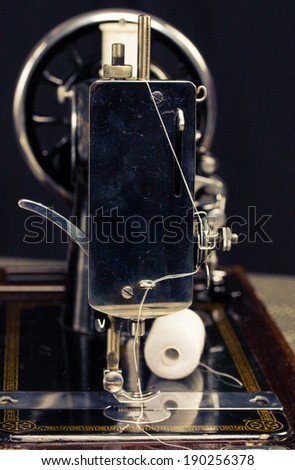 Vintage retro sewing machine with sewing equipment on a black background