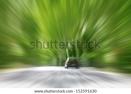 Car in motion blur driving alone a road in the forest.