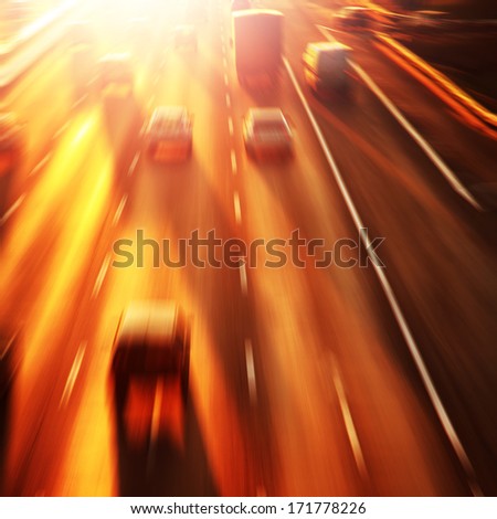 Cars in motion blur on highway during sunset.