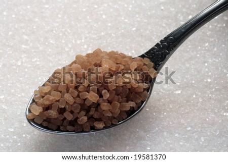 Spoon with brown sugar and white sugar as background.