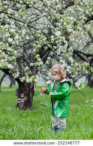 Boy with soap bubbles on blooming apple trees background