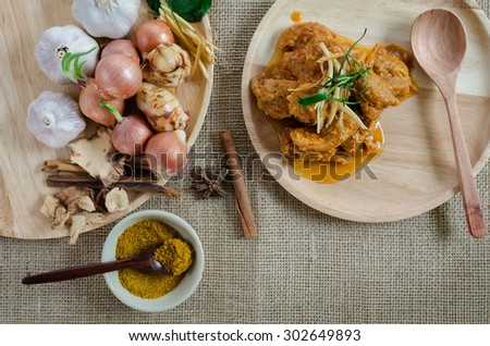 Spicy curry with ingredients and curry powder on the sackcloth background
