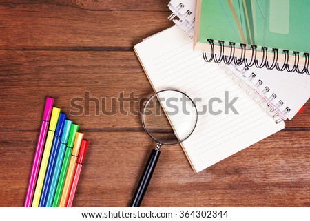 Directly above view of a old wooden table, office material, Note book, magnifying glass, pen color.