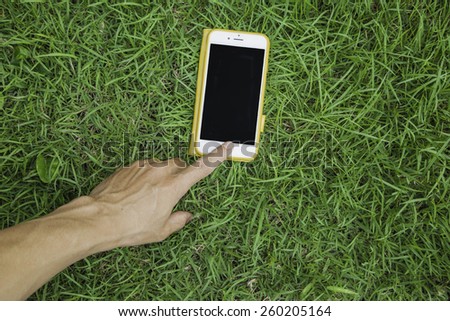Hand touch phone on the grass (Enter text space)