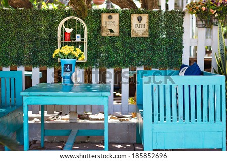 Blue vintage table and benches in front of a green hedge