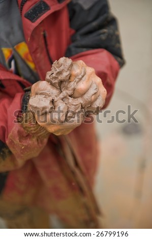 Young boy\'s hands squeezing clay/mud.