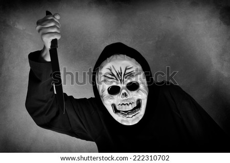 Woman in black with a plastic human skull mask holding a knife