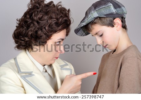 Woman scolding and pointing her index finger at the young boy. Vintage style photo