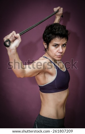 Woman with rubber band training in a gym isolated on purple background