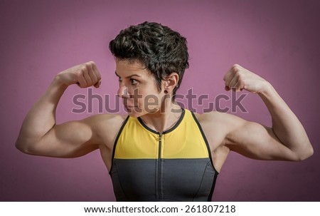 Woman training in a gym and showing her muscles isolated on purple background