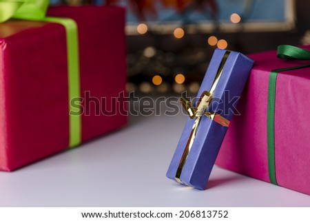 Wrapped presents.  Three presents wrapped in blue, red and magenta. Focus is on the golden bowknot, which complements the twinkles in the background.