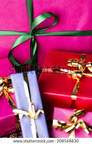 Emerald Bow Knot over Magenta Gift Box.  Close-up shot of a green bow tied around a magenta packet. Four smaller gift boxes with golden ribbons. All wrapped for any festive occasion.