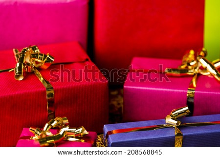 Tightly framed shot of plain-colored gift boxes in magenta, crimson and blue. Shallow depth of field. Background for any gift-giving occasion.