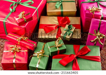 Bulk of plain presents grouped in red, gold, green and magenta. Shallow depth of field. Focus on front third. Background for any gift exchange.