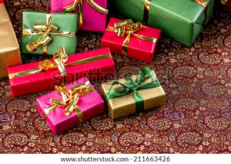 Small presents placed on a festive cloth. All wrapped in gold, red, green and magenta. Plenty of text space. Rich textures. Shallow depth of field.
