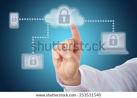 Raised index finger touching a locked cloud icon linked via dotted lines to mobile and tablet devices within a network. Cell phone, tablet and laptop computer all display the lock on-screen. Close up.
