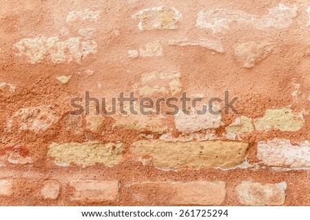 Texture of a medieval brick wall. Warm sienna and ocher in color. Venetian red plaster chipping off. Grainy surface, but relatively even. Two-dimensional background. Close up shot outdoors on tripod.