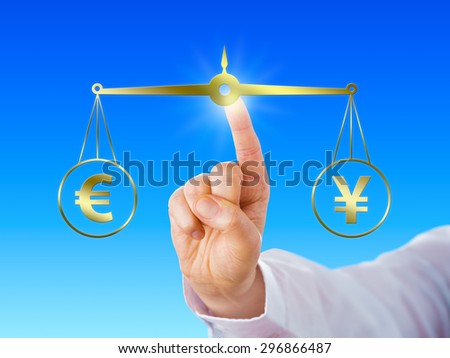 Index finger of a white collar worker is equating the European Union currency sign at par with the Japanese yen symbol on a virtual golden scale over light blue background. Financial metaphor.