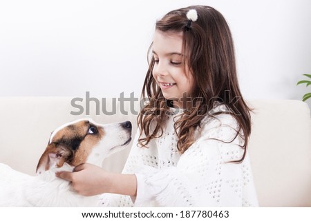 Little girl playing with pet dog in living room