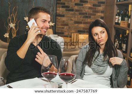 Bad date. Man talking on the cell phone while his girlfriend or wife is making angry expression gesture