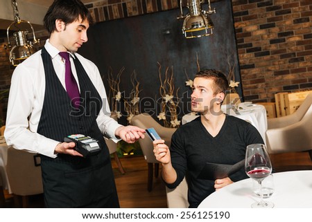 Waiter taking a payment by credit card at the restaurant