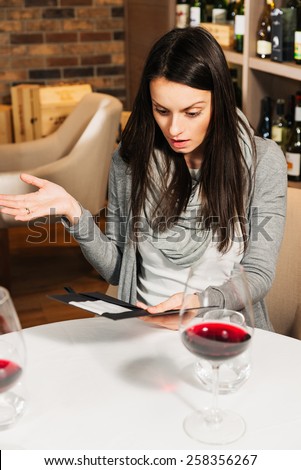 A young attractive woman is shocked at her restaurant bill