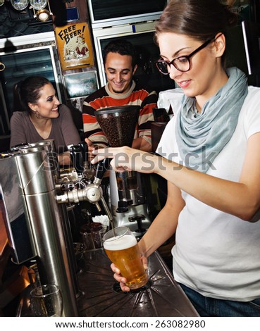 Female bartender pours the beer into a glass