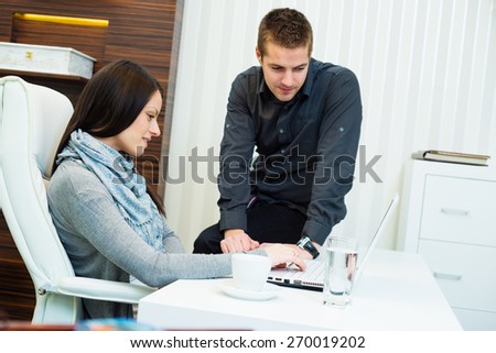 Young business woman working together with his colleague on laptop in office