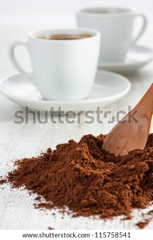 Wooden spoon with freshly ground coffee and a cup