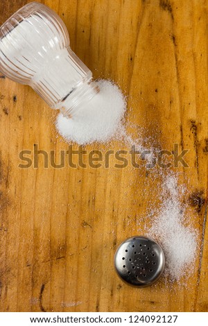 Spilled salt shaker on wooden table