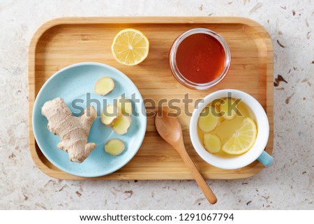 Lemon and ginger tea with honey. Wooden tray of honey lemon tea with fresh ginger root.