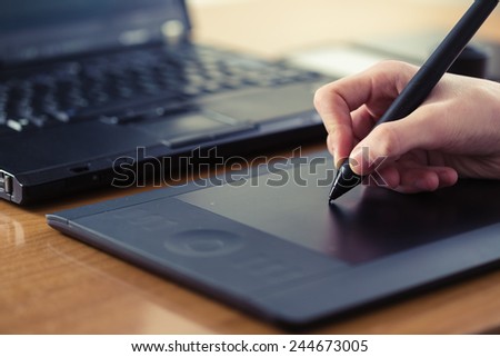 Hand is drawing on a digital graphic tablet with pen