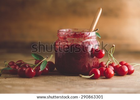Jar of cherry jam, sour cherries and spoon