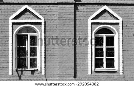 two windows with barred on the outside wall of an old stone house