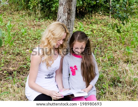 mother and the child read the book on a glade