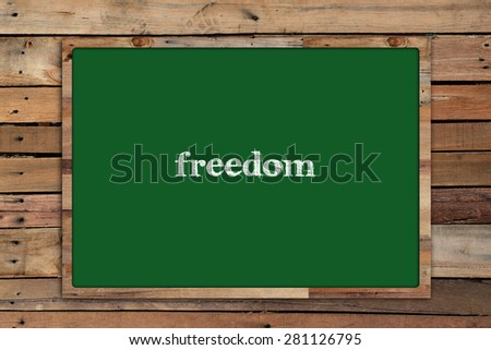 'freedom' write on Green board on wood background