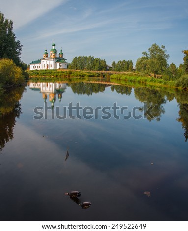 The picturesque white church on the river bank and its reflection in the water, Karelia, Russia