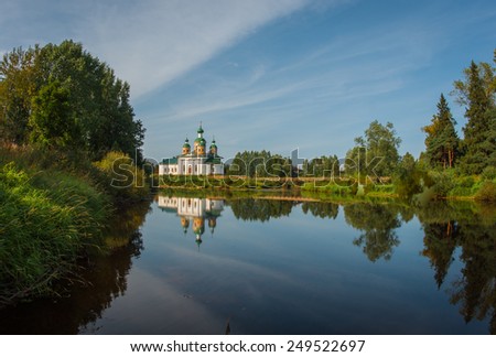 The picturesque white church on the river bank and its reflection in the water, Karelia, Russia