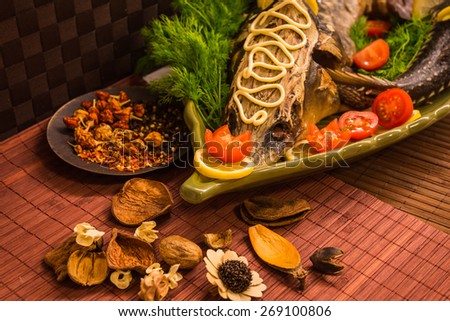 Image of a sturgeon decorated with lemon and tomatoes on a green plate