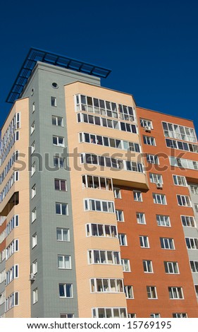 New modern brick multistory house on blue sky background in three colors: red, yellow, grey. Deep blue sky