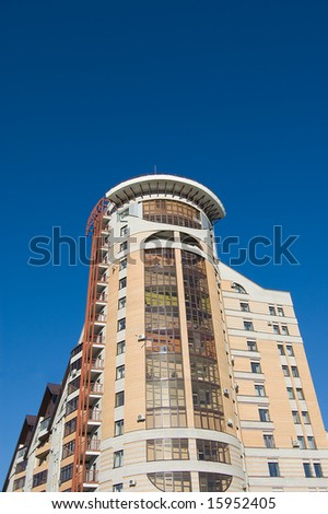 New modern brick multistory house on deep blue sky background in three colors: brown, yellow, grey