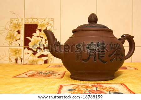 Brown clay teapot on bright yellow tablecloth