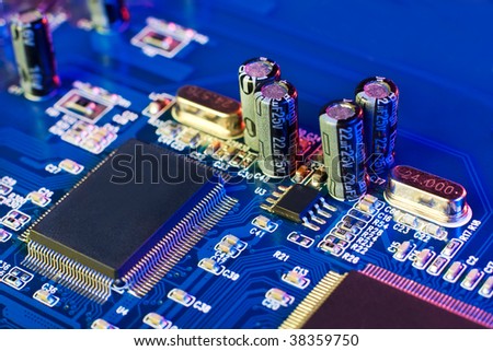 Technology: capacitors and chips on blue microcircuit board in multicolor light. No logos or brandnames