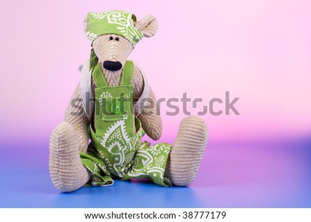 Sad sitting toy with rucksack on color background