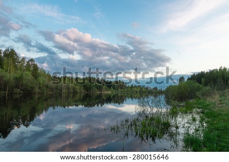 Evening landscape on a pond with wood reflexion in water, Russia, Ural Mountains