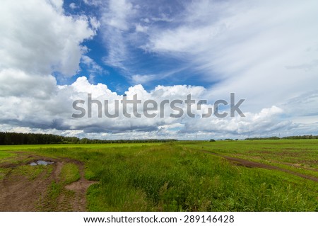 Rural field with clouds in the summer with a dirt road, Russia, Ural Mountains
