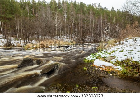 first snow in the woods on the banks of a rapid river, Russia, Ural