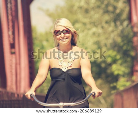 attractive woman riding classic bike on bridge on sunny day with soft light filter