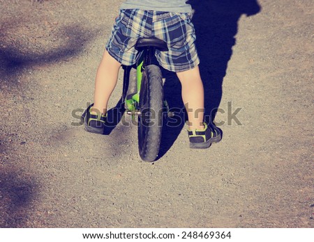 abstract view of toddler riding bike on gravel path with retro instagram filter (shallow depth of field - focus is on planted foot)
