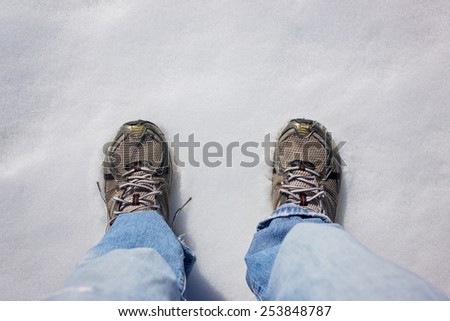 legs and tennis shoes standing on fresh thawing snow with a drama filter (shallow depth of field)
